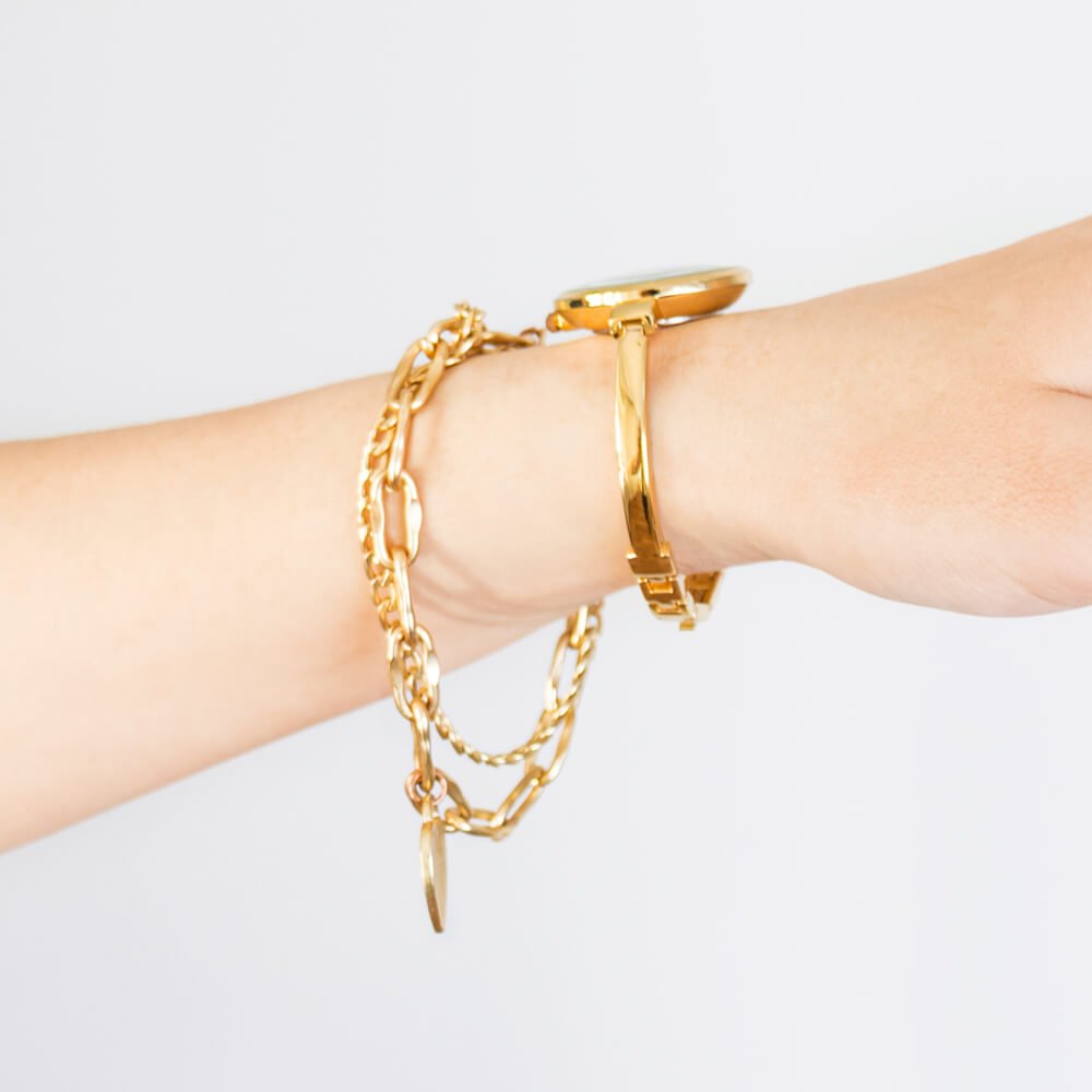 Close-up of a woman’s wrist wearing layered gold bracelets